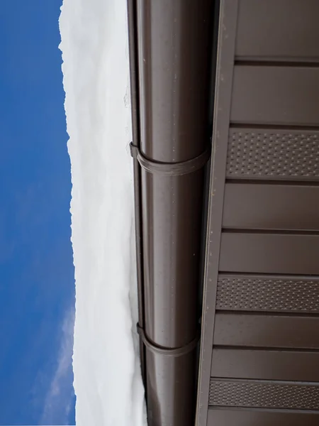 Snow hanging on the roof drainpipe. The drainpipe are covered with snow. — 图库照片