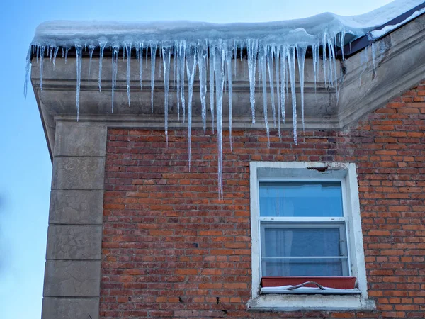 Large winter icicles hanging from the house roof — Stock Fotó
