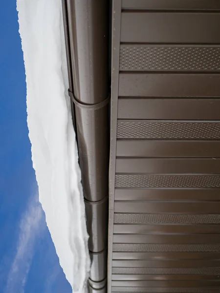Snow hanging on the roof drainpipe. The drainpipe are covered with snow. — Fotografia de Stock