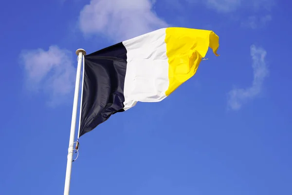 アルカコン町の旗南西フランスの白い黒い黄色の空に青い空に空気中に手を振って — ストック写真