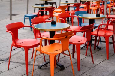 Cafe Cafe Cafe 'de kırmızı ve turuncu sandalyeler ve renkli çelik masalar.
