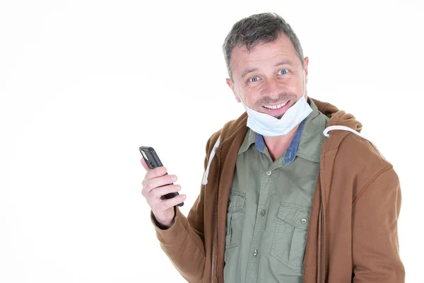 Sorrindo Homem Amigável Segurando Seu Telefone Celular Tira Máscara Cirúrgica — Fotografia de Stock