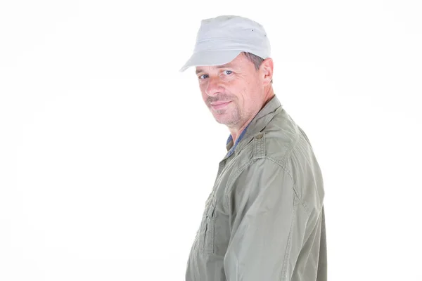 中年男で緑のシャツとキャップ笑顔プロフィール側ビュー上の白の背景とルッキングカメラ — ストック写真