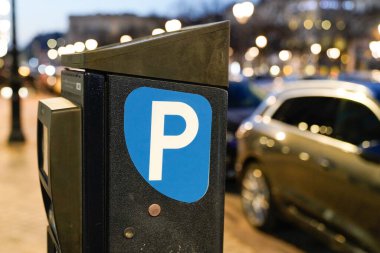 Gece yarısı şehir sokağına park etmiş park sayacı mavi beyaz araba.