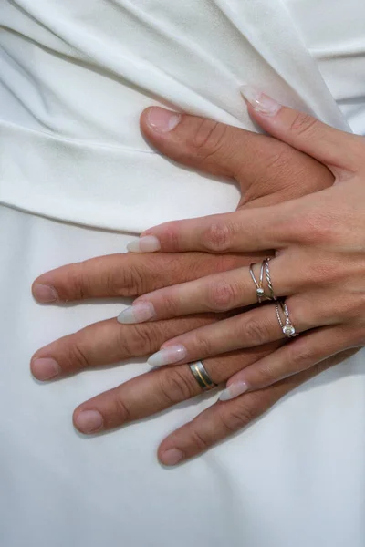 wedding couple rings fingers bride and groom hands on marriage wed white dress background