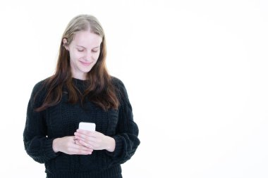 Beyaz arka planda izole edilmiş cep telefonu mesajları kullanan gülümseyen sarışın beyaz kadın portresi