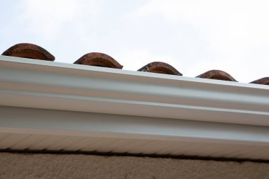 White gutter new modern on the roof top of house clipart