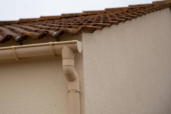 plastic edge of a roof gutter with clips and edge of shingles