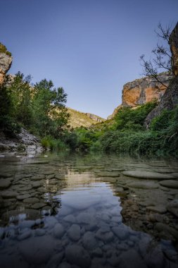 Sakin bir nehir, dağın eteklerinde gezinti yapıyor.
