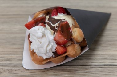 Dilimlenmiş çilekli waffle külahı ve mükemmel tatlı için krem şantili krema..