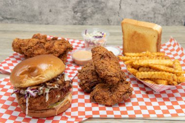 Çıtır çıtır ve baharatlı tavuklu sandviç, kanatlar, patates kızartması, Cole, lahana, çiftlik ve gizli sosla servis edilen şeritler..