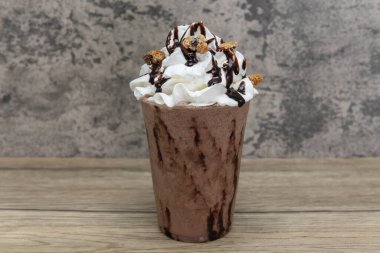 Bu tatlı buzlu içeceğin üzerine kurabiye parçaları serpiştirilmiş krema ve şekerleme.