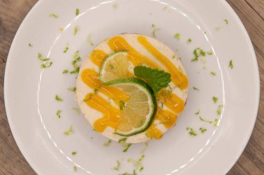 Krema, limon dilimi ve nane yaprağıyla süslenmiş ferah limonlu turtanın genel manzarası.