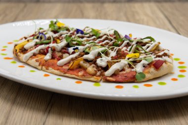 Sağlıklı sebze sosu ve ince kabuklu dekore edilmiş tabakta oval şekilli düz ekmek pizzası..