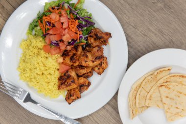 Pilav, salata ve pide ile servis edilen mükemmel ızgarada pişirilmiş tikka tavuğu manzarası sağlıklı bir Akdeniz yemeği için..