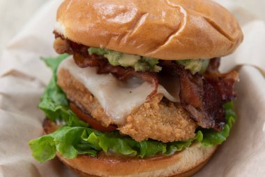 Kızarmış peynirli, pastırmalı, marullu ve domatesli kızarmış tavuklu sandviç..