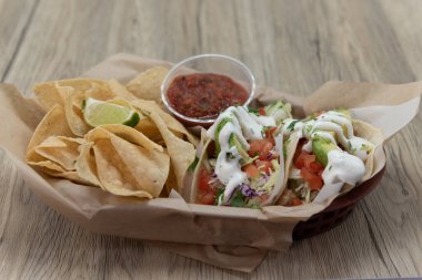 Üç balıklı tako ile yenecek içi cips ve salsa dolu bir sepet..
