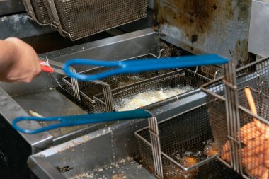 Kavurucu sıcak yağ kızartması soğan halkaları, kalamar halkaları ve restoranın mutfağında patates kızartması..