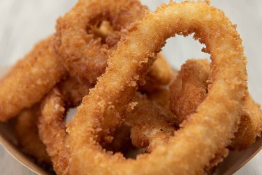 Çıtır çıtır soğan halkalarının dokusunu kapatın. Kartondan bir teknede yemek var..