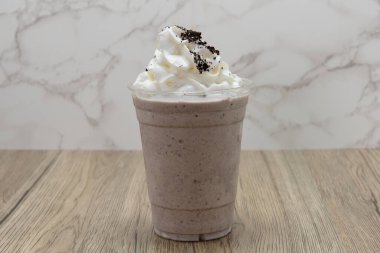 Çikolatalı kurabiye milkshake soğuk ve soğuk bir bardakta servis edilir ve üzeri krema ile kaplanır..