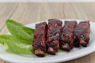 Barbekü kaburgaları sosla kaplanır ve marul ile süslenir..