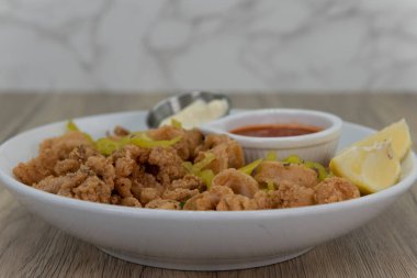 Dilimlenmiş biber, tarter ve kokteyl sosuyla karışık kalamar halkalarıyla dolu çıtır bir kase..