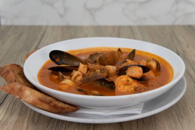 Dilimlenmiş kalamar, midye ve midye dolu büyük bir kase deniz ürünü ve kabuklu balık cioppino..