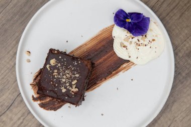 Yemekten sonraki tatlı manzarası üzerine ezilmiş fındıklı zengin bir parça çikolatalı pasta içerir..