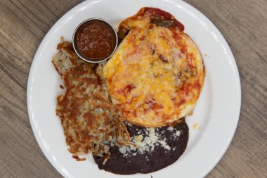 Overhead view of huevos rancheros with eggs, refried beans, hashbrowns for a delicious Mexican breakfast meal to start the day.