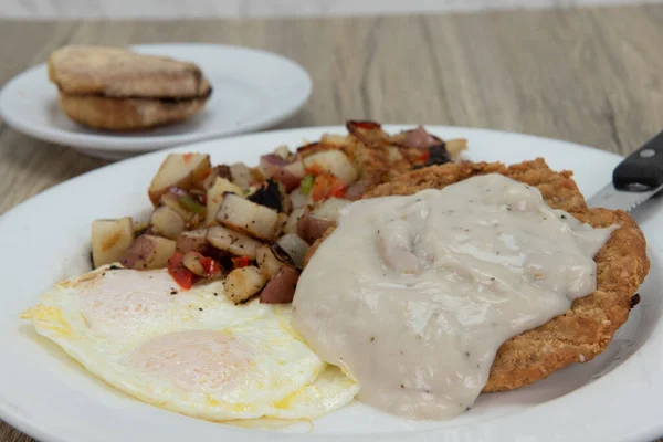 Hunger will no longer exist after eating this breakfast consisting of chicken fried steak, covered with country gravy, and served with fried eggs, potatoes, and toast.