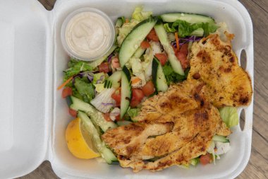 Tavuklu ızgara salata siparişi, köpük kutusunu tamamen dolduruyor..