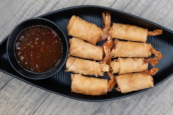 Overhead view of crispy shrimp egg roll for a Vietnamese meal appetizer served in a boat.