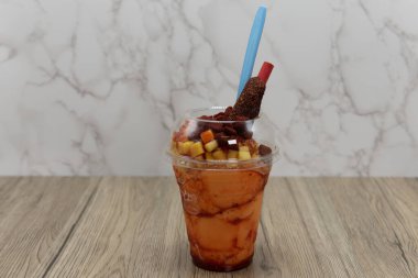 Lezzetli, buz gibi mango aromalı, mangoneada smoothie. Yanında kaşık ve samanla servis edilen meyve parçaları..