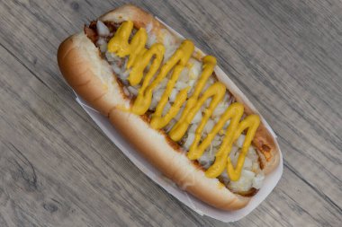 Hardal şeritlerinin yukarıdan görünüşü soğan kokan geleneksel acılı sosisli sandviçi süslüyor..