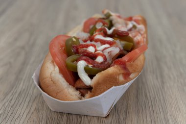 Lezzet patlaması için dilimlenmiş jalapeno, domates ve krem peynirli baharatlı sosisli sandviç..