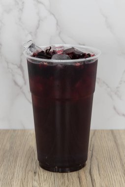 Susamış bir iştah için lezzetli su freska içeceği. Plastik bardakta servis edilen koyu meyve suyu..