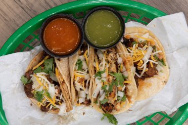 Fast food sepetinde servis edilen tavuk, biftek ve domuz eti de dahil olmak üzere çeşitli takoların genel manzarası..