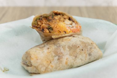 Fast food sepetinde servis edilen et, peynir, fasulye ve pirincin yarısına kesilmiş domuz sucuklu burrito..