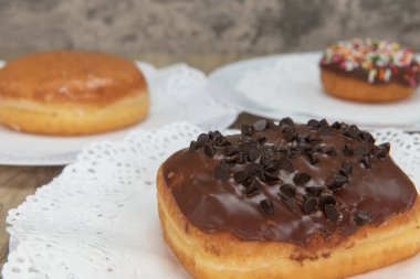 Fırından getirilen çikolatalı donutla birlikte fırından taze taze taze donutlar tabakta servis ediliyor..