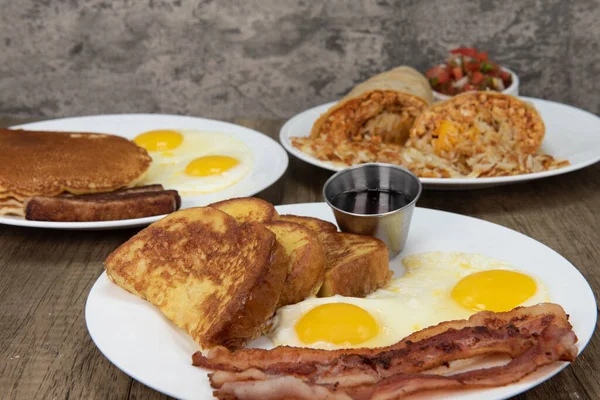 Standard American breakfast choices layed out on the table as a buffet feast of french toast, pancakes, or burrito.