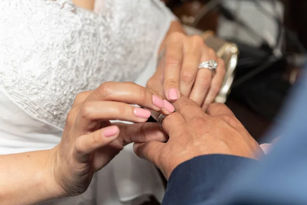 Bride placing ring on finger of the groom during the wedding ceremony of marriage.