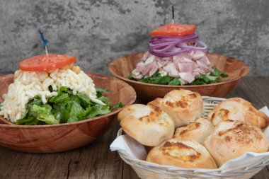 Italian food feast is set up on the table with two salads to choose from or a basket of garlic and cheese rolls.