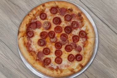 Overhead view of hot from the oven is a crispy crust Italian baked pepperoni pizza that is ready to eat.