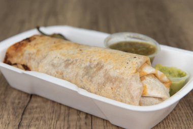 Loaded mexican cuisine burrito, bulging at the flour tortilla and served with a grilled jalapeno, salsa, and guacamole.