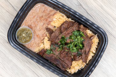 Overhead view of take out order of ranchera with rice and beans is conveniently packed in a microwavable container.