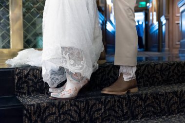 Bride and groom showing off their cowboy and cowgirl boots during the wedding ceremony.
