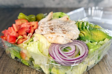 Öğle yemeği, içi malzemelerle dolu ızgara tavuk göğsü salatası ve dilimlenmiş avokado ile servis edilir..