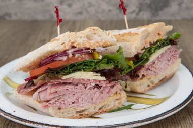 Doldurulmuş İtalyan sandviçi jambon, peynir, pepperoni, domates ve taze pişmiş rulo soğanla doludur..