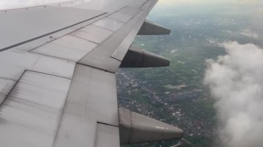 Aircraft window view wing flying from above air. Beautiful aerial view landscape airplane clouds video in the evening. Airline travel or aviation jet. Atmosphere nature.