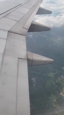 Aircraft window view wing flying from above air. Beautiful aerial view landscape airplane clouds video in the evening. Airline travel or aviation jet. Atmosphere nature.